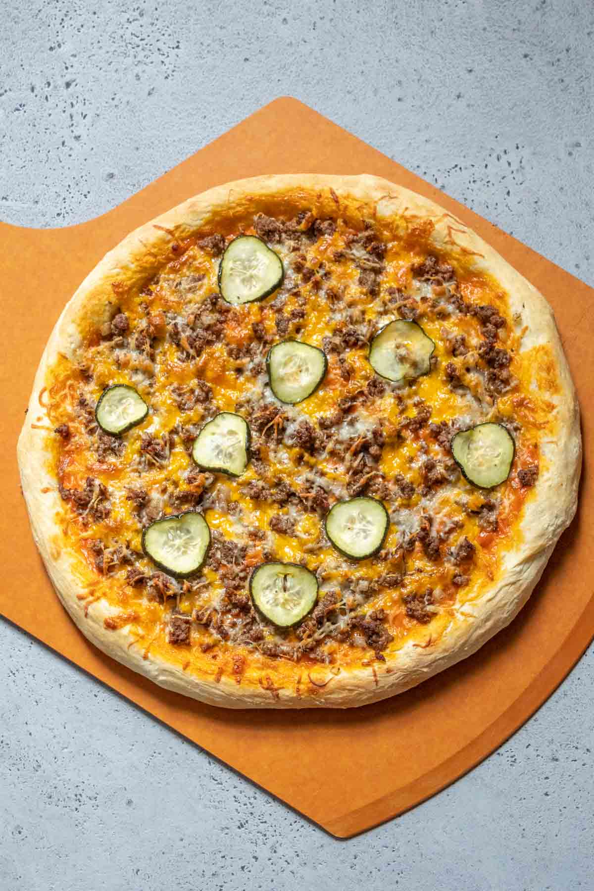 Baked cheeseburger pizza on a pizza peel.