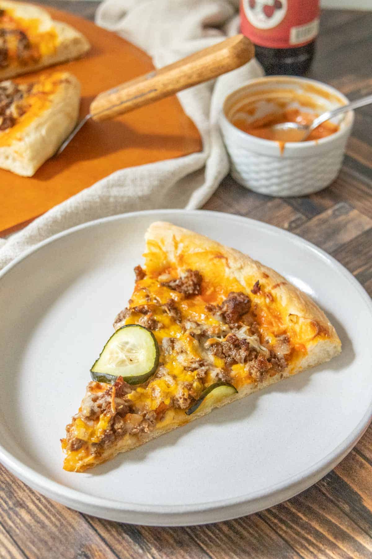 Slice of cheeseburger pizza on a gray plate.