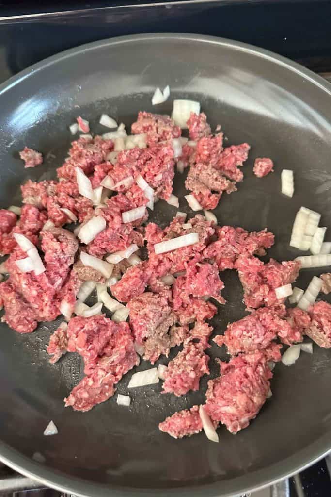 Cooking ground beef and chopped onion in a saute pan.