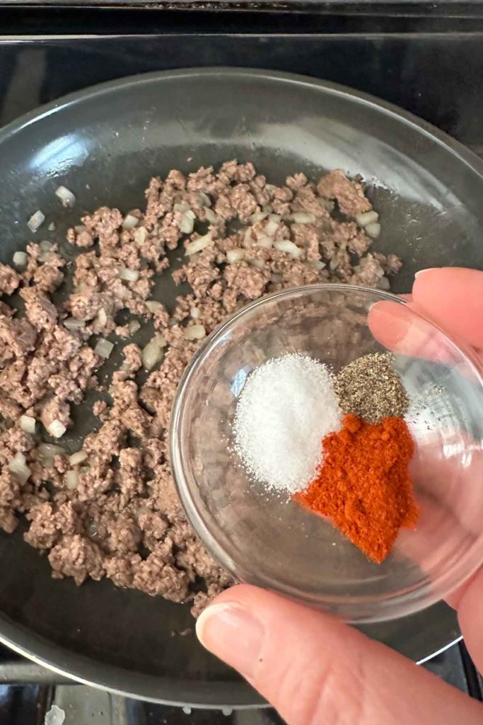 Spices in a small bowl to be added to cooked ground beef and onion.