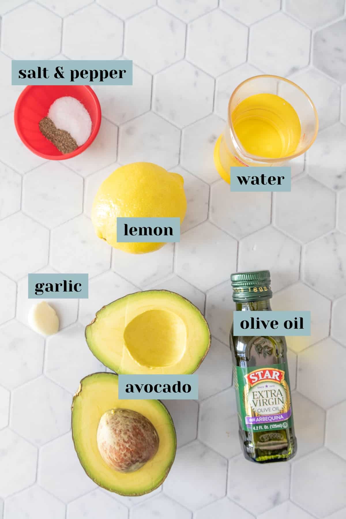 Ingredients for avocado dressing on a tile surface with labels.