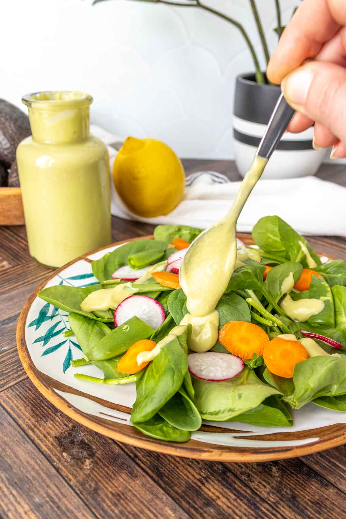 Dolloping avocado dressing on a spinach salad.