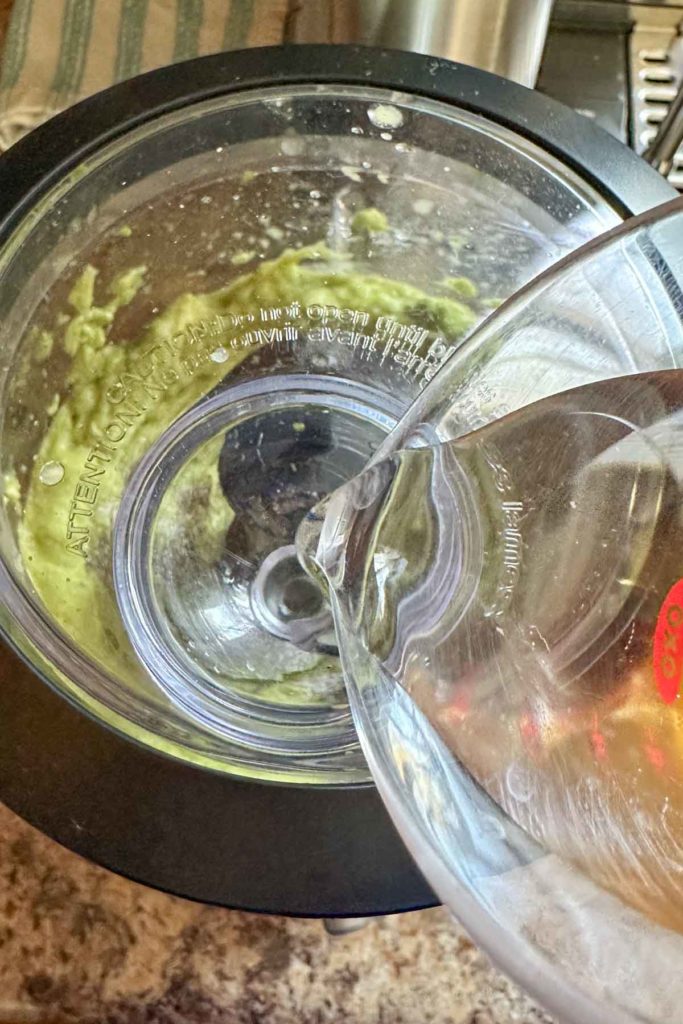 Pouring water into the feeder tube of a food processor.