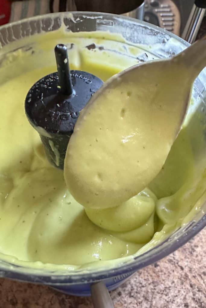 Blended avocado dressing in a food processor.