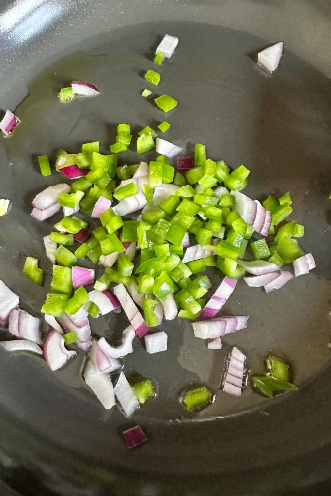 Onion and green pepper in a frying pan.