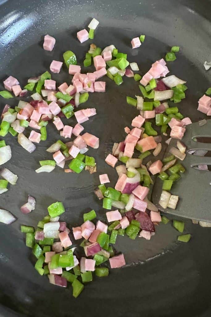 Sauteeing ham, onion, and green pepper in frying pan.