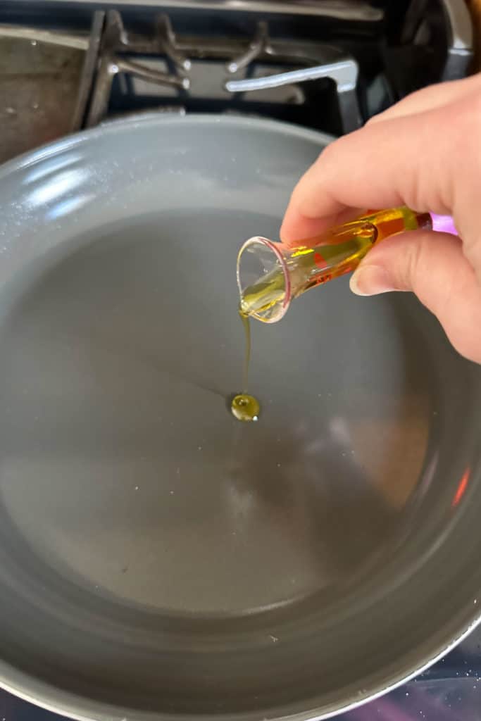 Pouring olive oil into a frying pan.