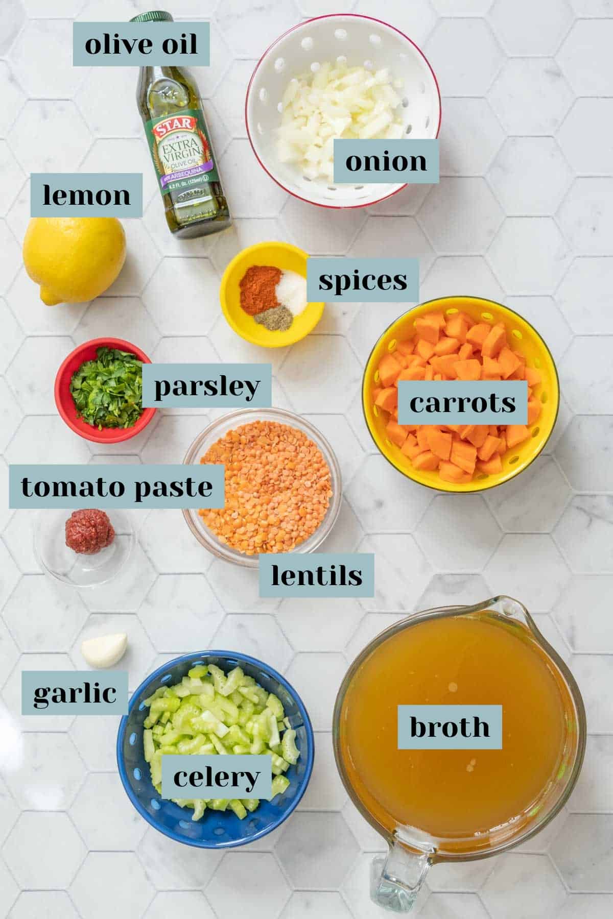 Ingredients for red lentil soup on a tile surface with labels.