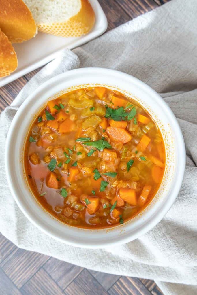 White bowl of red lentil soup with a tan napkin underneath.