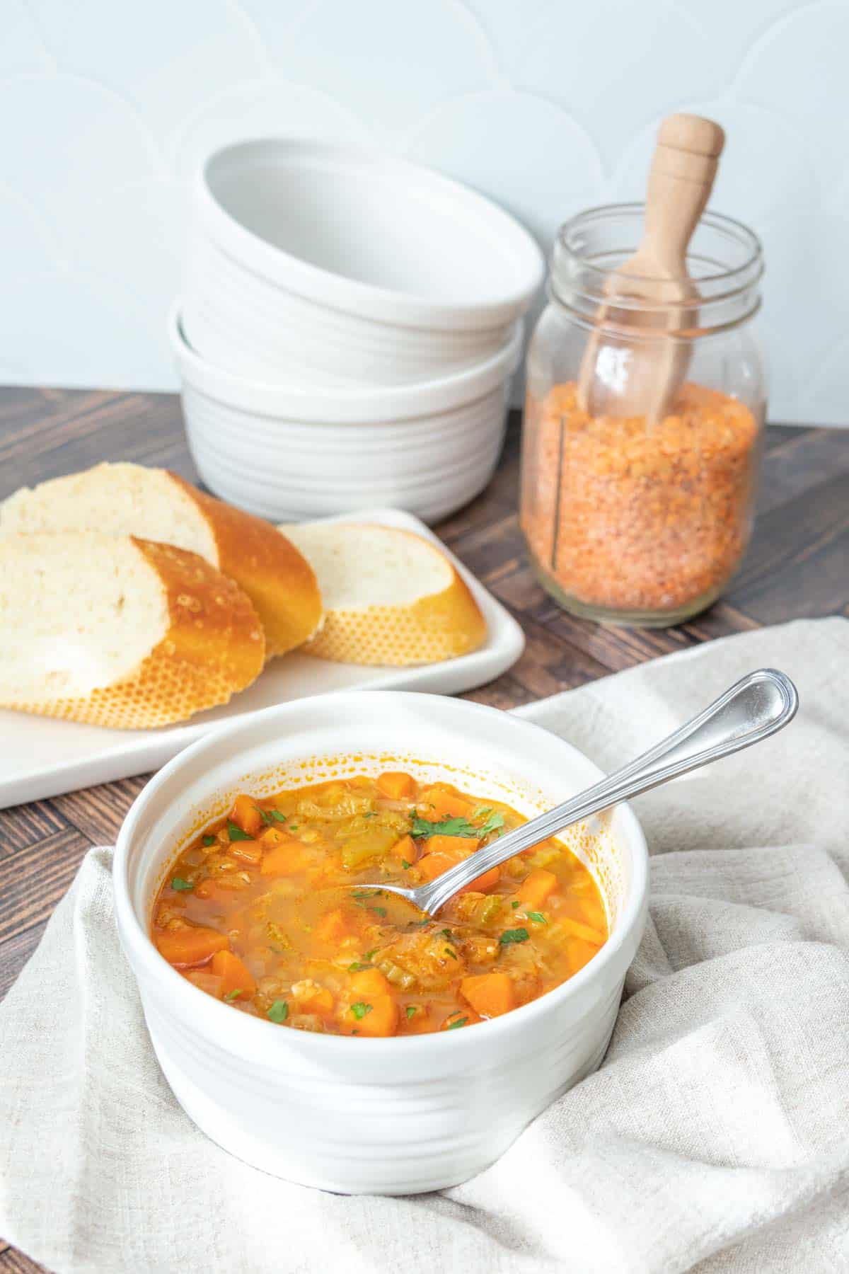 White bowl of red lentil soup with spoon in it.