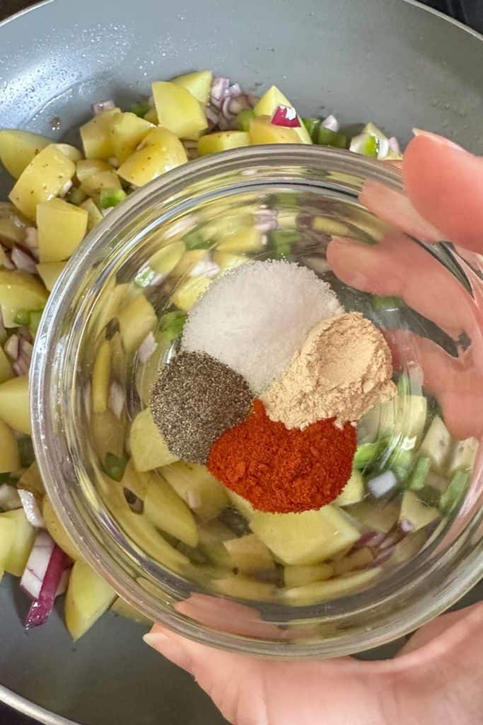 Adding spices to potatoes.