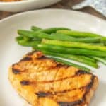 Plate with a teriyaki pork chop and sauteed green beans.