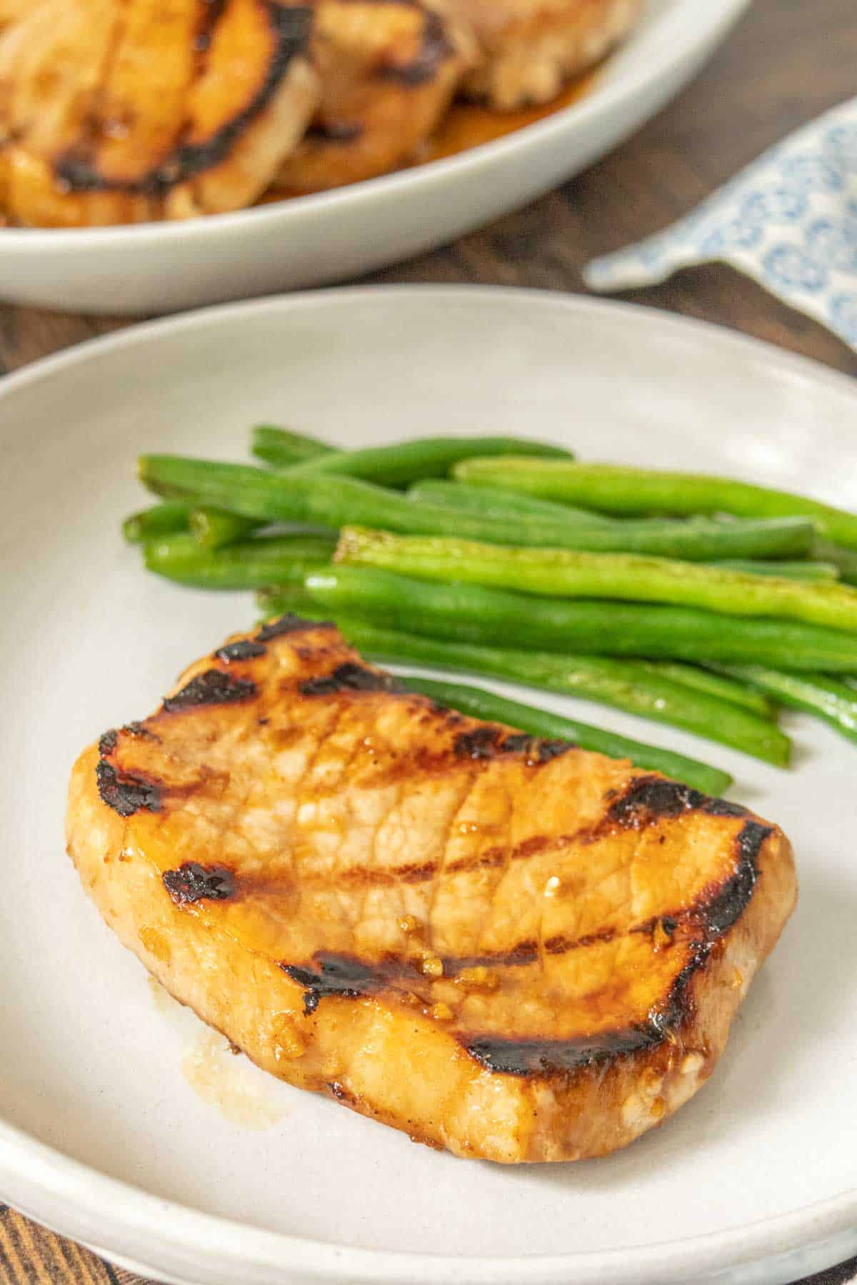 Plate with a teriyaki pork chop and sauteed green beans.