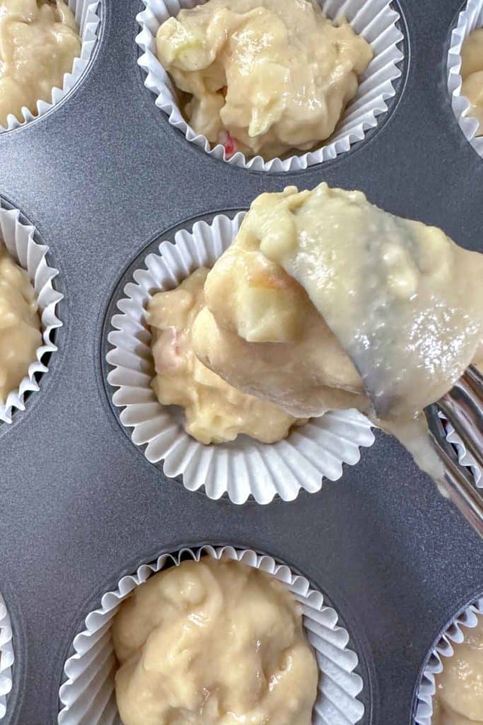 Scooping apple muffin batter into pan.