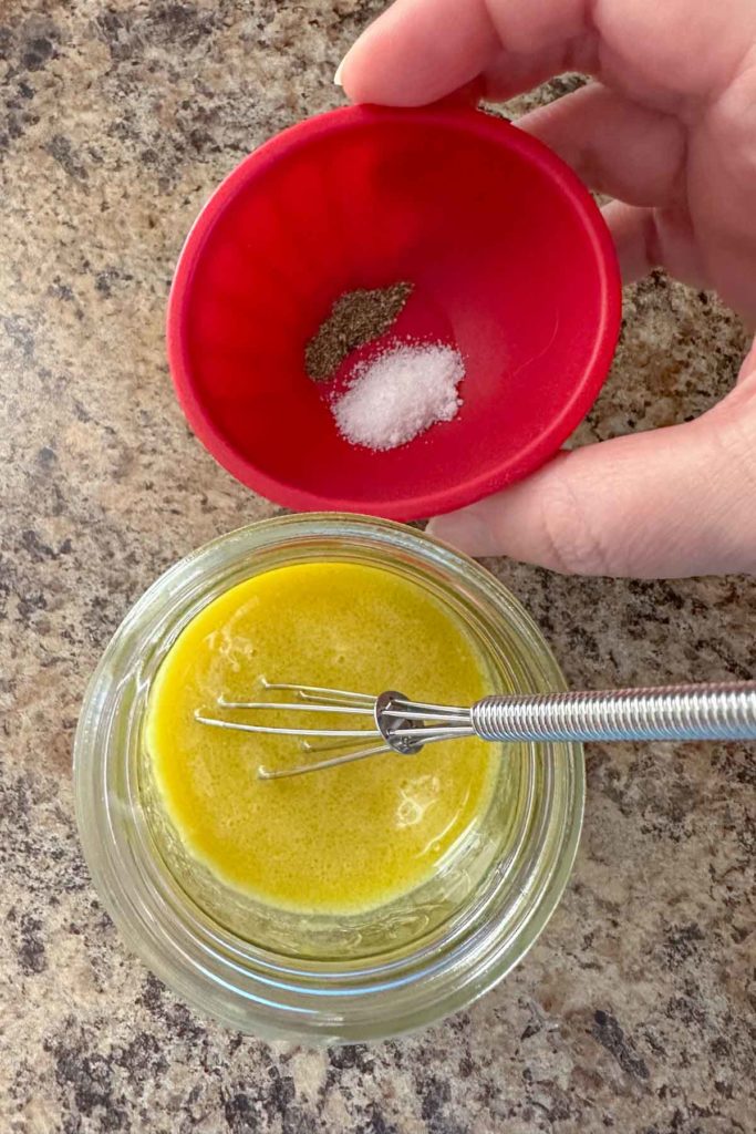 Salt and pepper in a small red bowl to add to dressing.