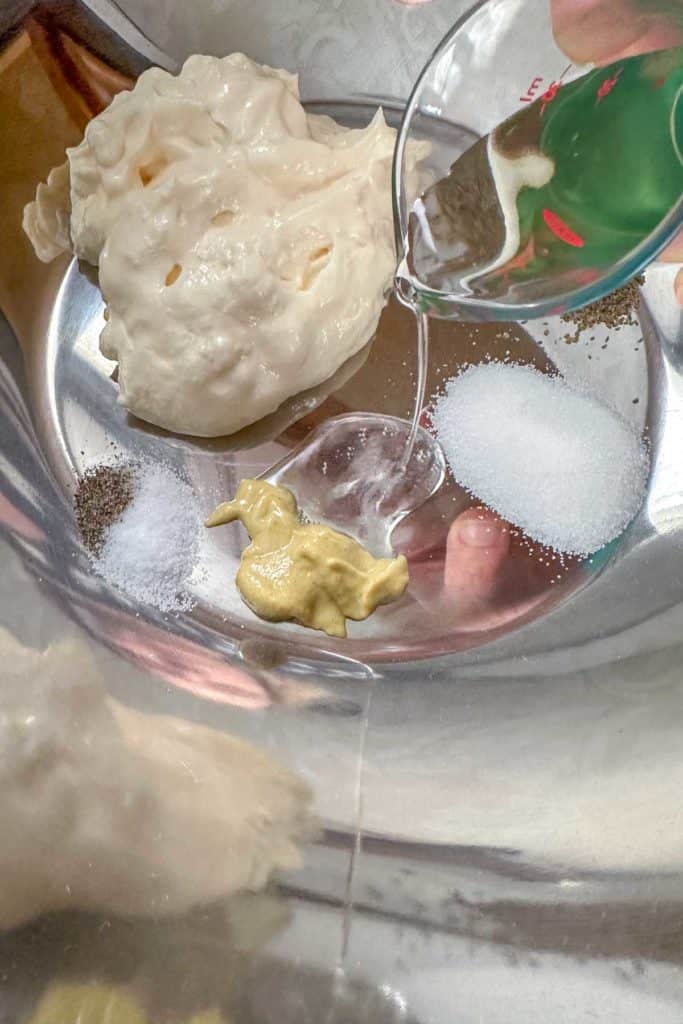 Ingredients for homemade coleslaw dressing in a metal mixing bowl before mixing together.