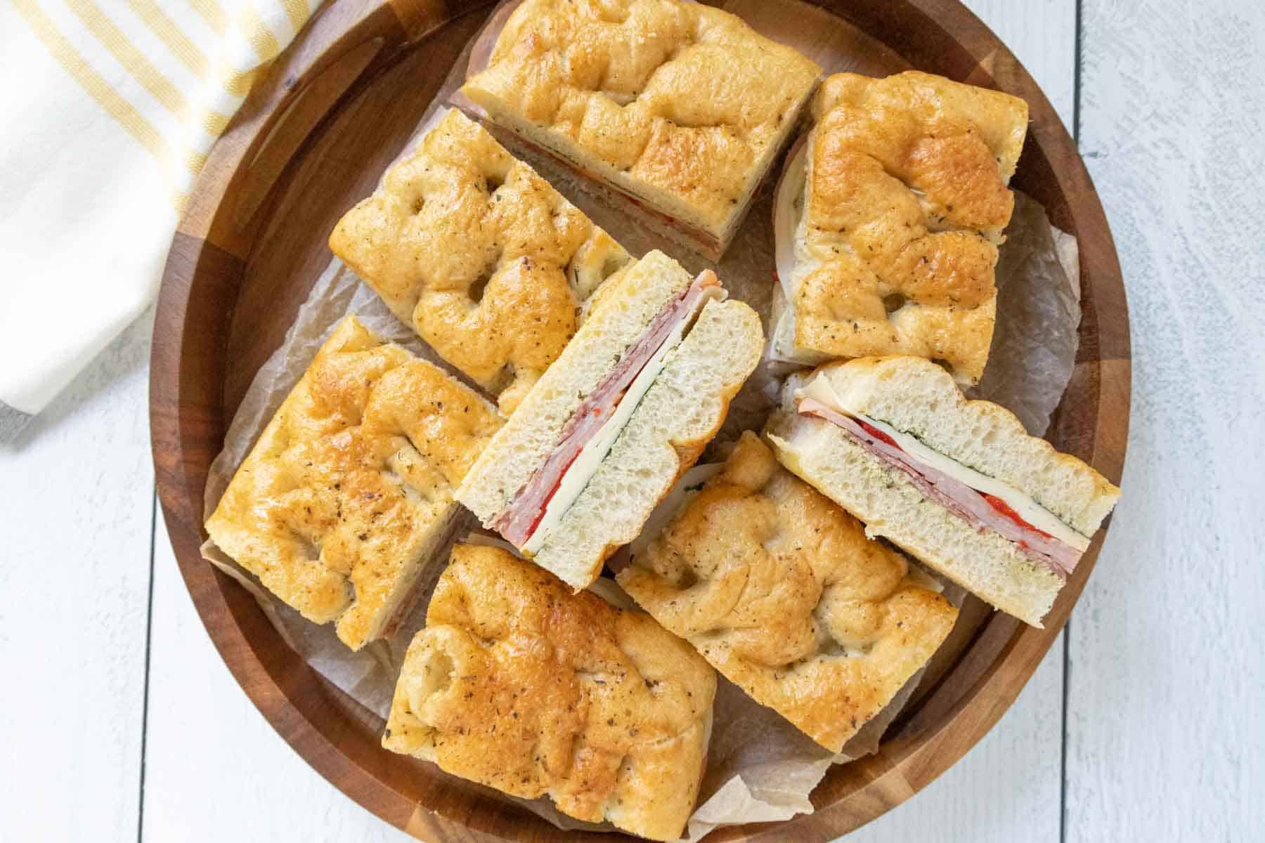 Overhead view of a wooden serving tray of sliced pressed Italian sandwiches.