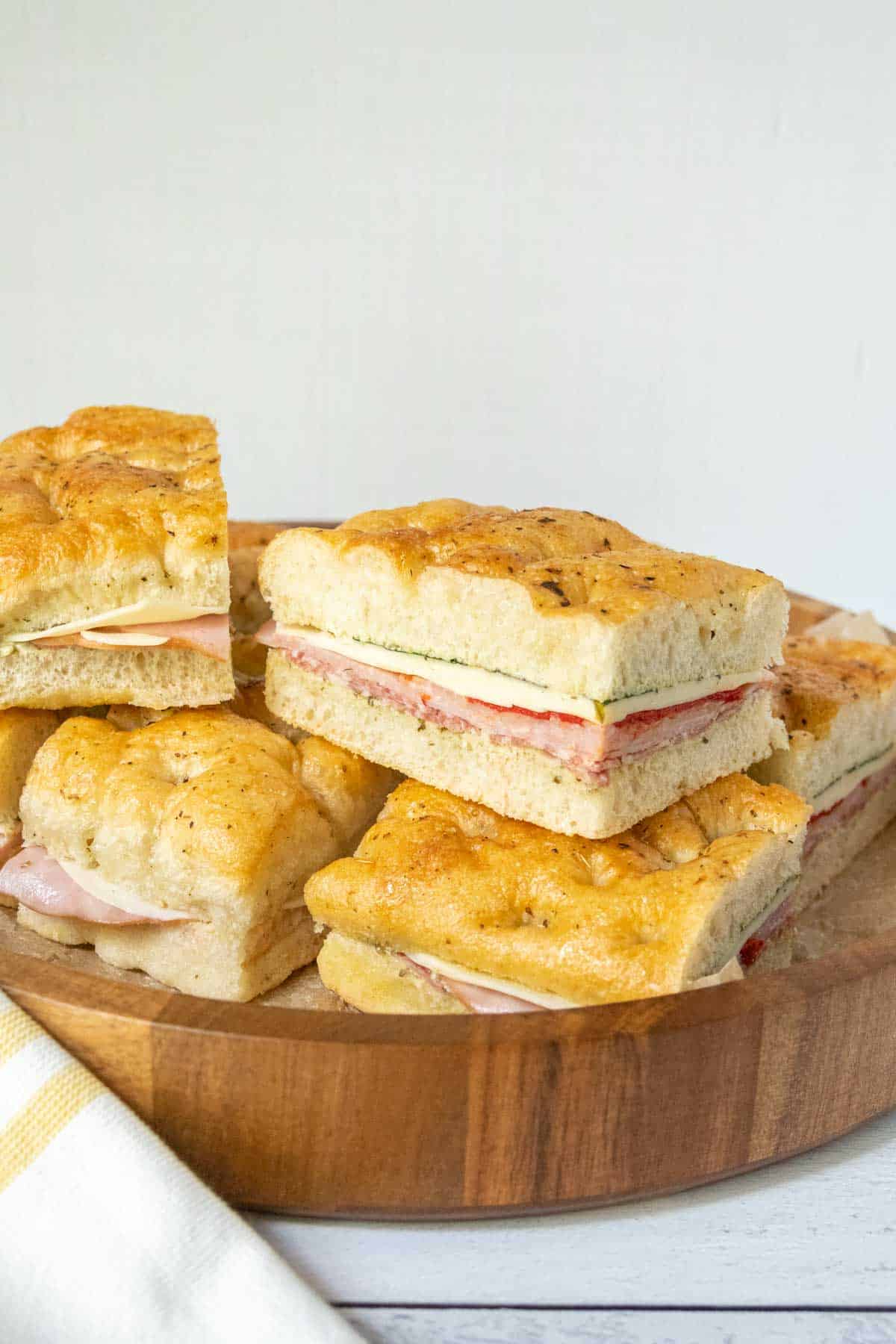 Wooden serving platter with pressed Italian sandwiches.