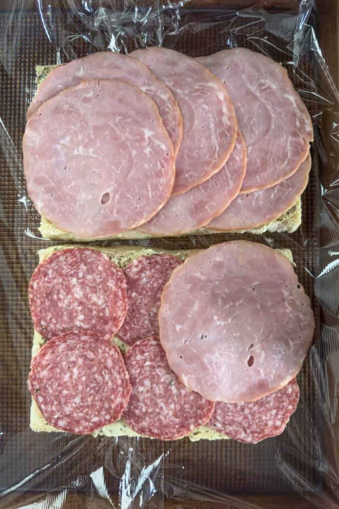 Layering meat on sandwich.
