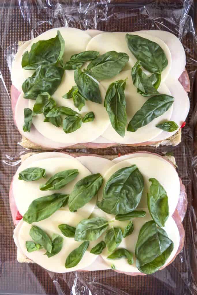 Topping sandwich with basil leaves.