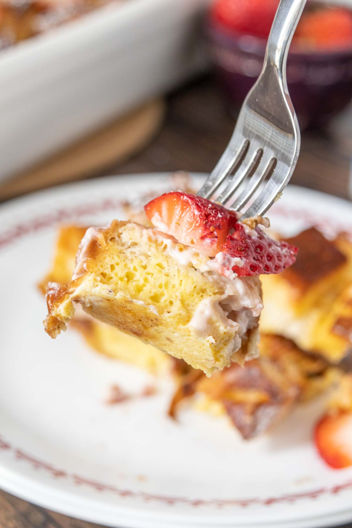 Fork holding up a bite of strawberry french toast.