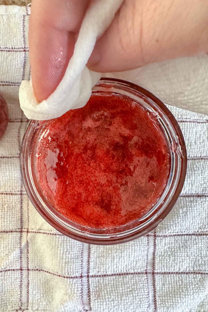 Wiping rim of jam jar with a wet paper towel.