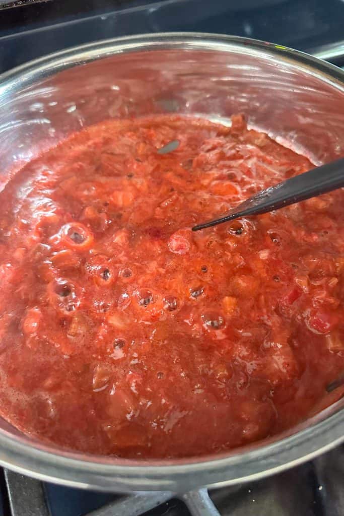 Strawberries and rhubarb being cooked in a saucepan to make jam.