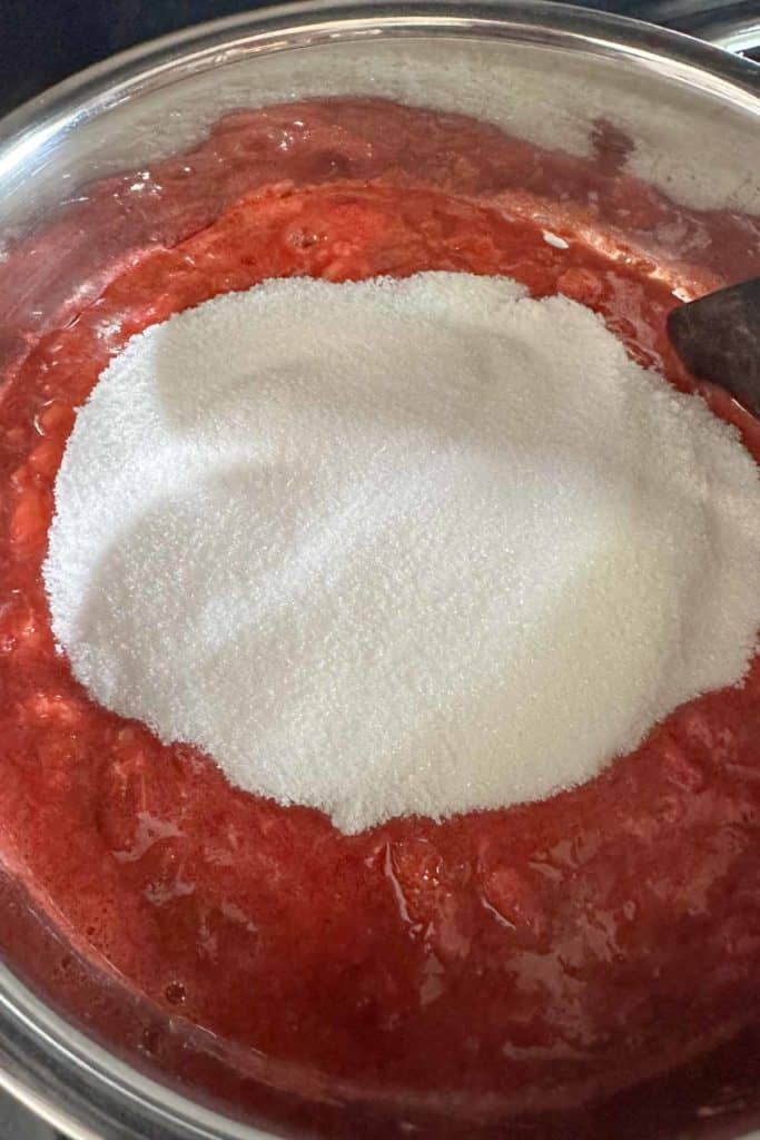 Sugar added to a saucepan of strawberry rhubarb jam.