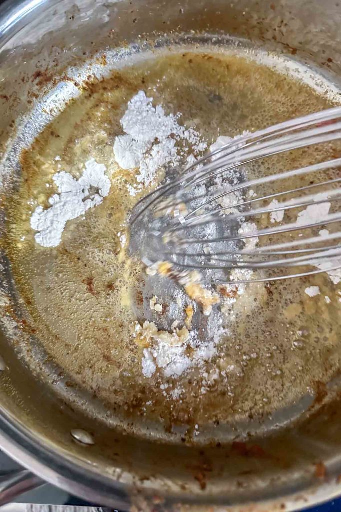 Whisking flour into melted butter in a saucepan.