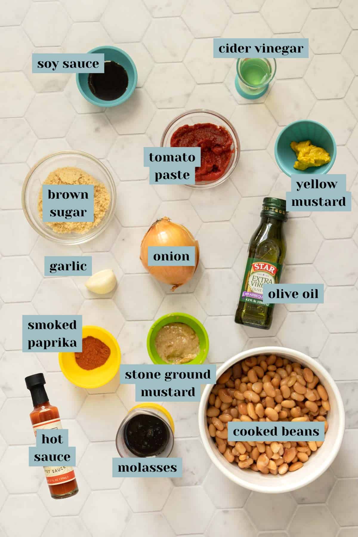 Ingredients for vegetarian baked beans on a tile surface with labels.