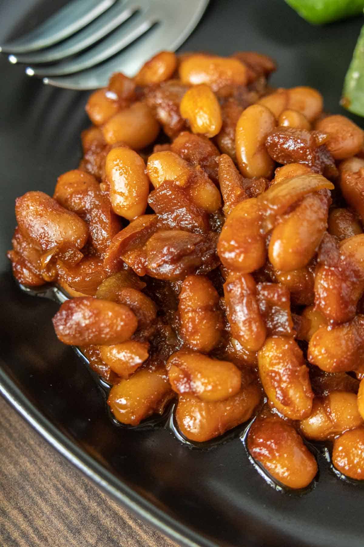 Close up of vegetarian baked beans on a black plate.