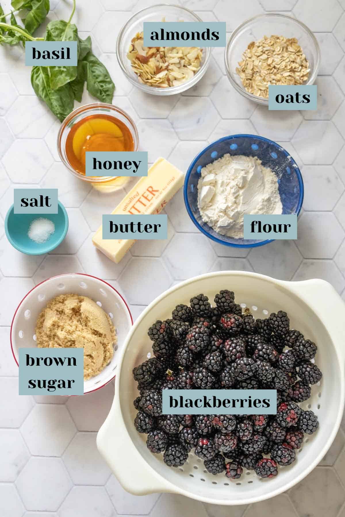 Ingredients for blackberry crisp on a tile surface with labels.