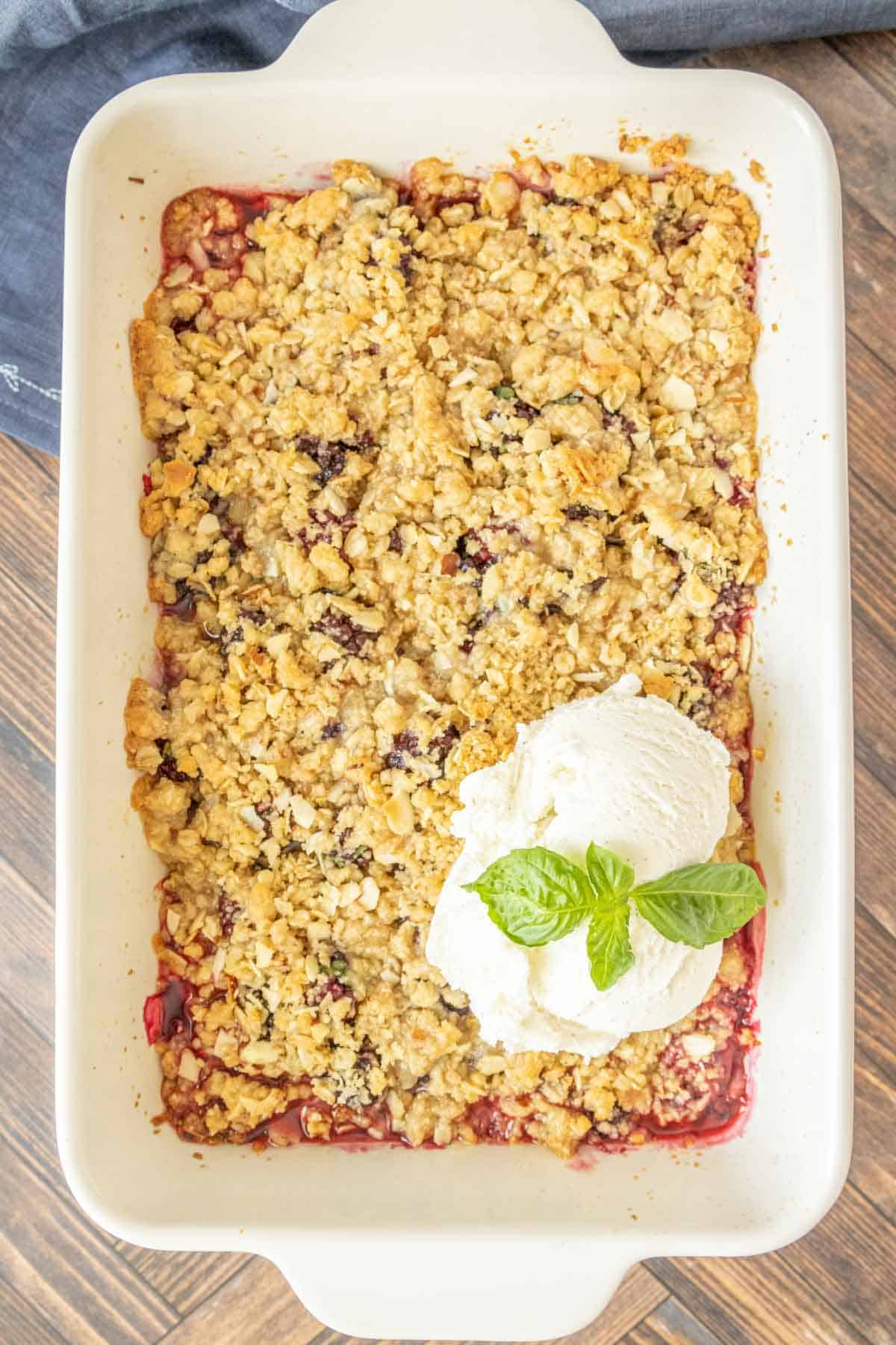 Overhead of baked blackberry crisp with ice cream on top.