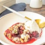 Shallow bowl of blackberry crisp with a scoop of ice cream.