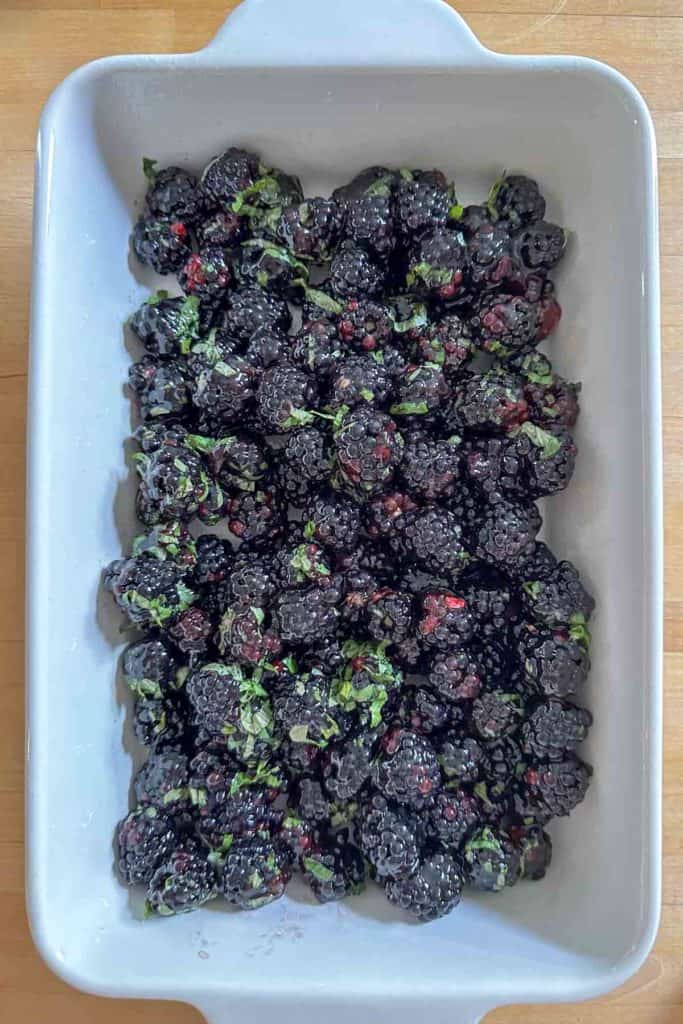 Blackberries and basil in a white casserole dish.