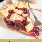 A slice of homemade cherry pie with a golden lattice crust sits on a plate beside a fork and a cup, showcasing its vibrant cherry filling.