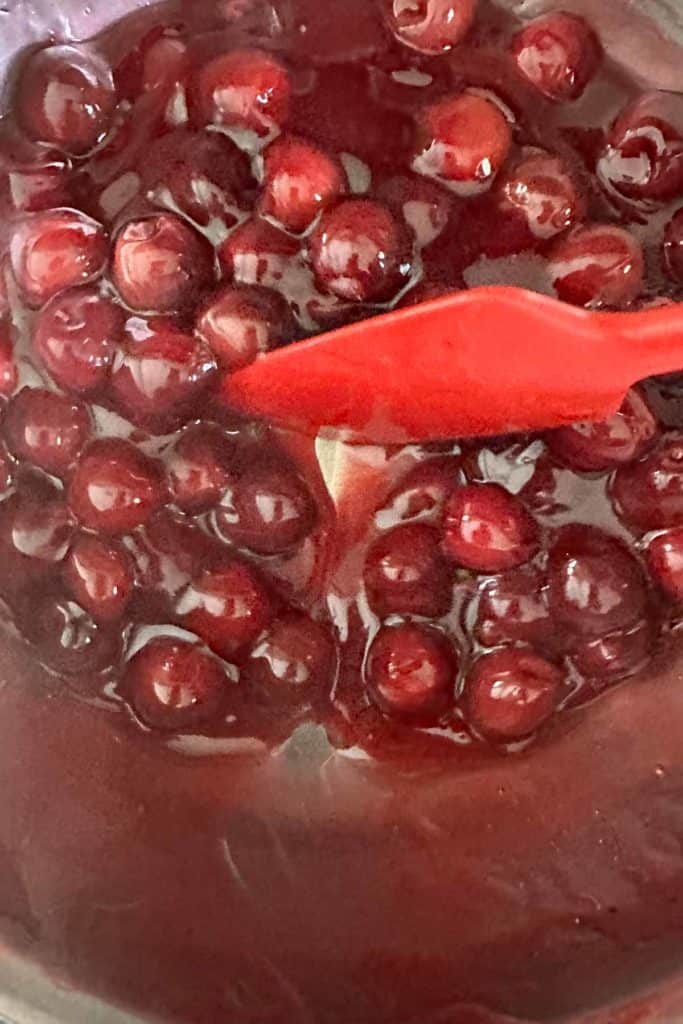 Thickening cherry pie filling in a saucepan.