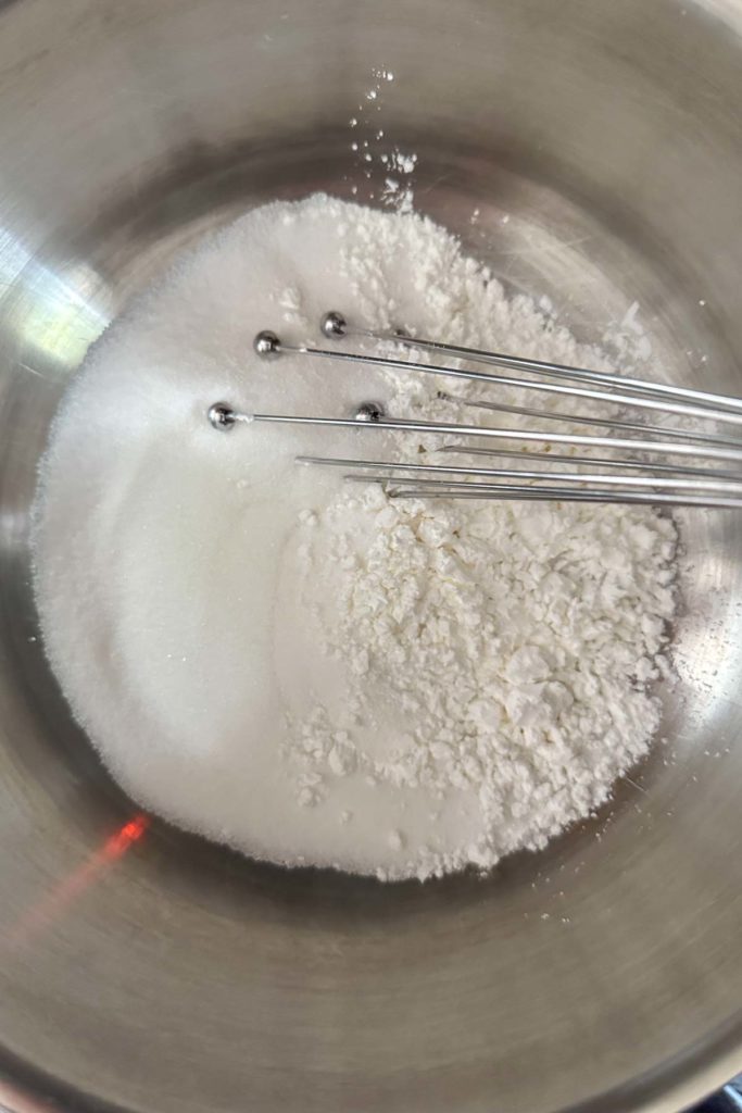 Whisking together sugar and cornstarch in a saucepan.