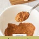 A spoonful of homemade taco seasoning held over a white bowl filled with more homemade taco seasoning; text overlay reads “homemade taco seasoning.”.