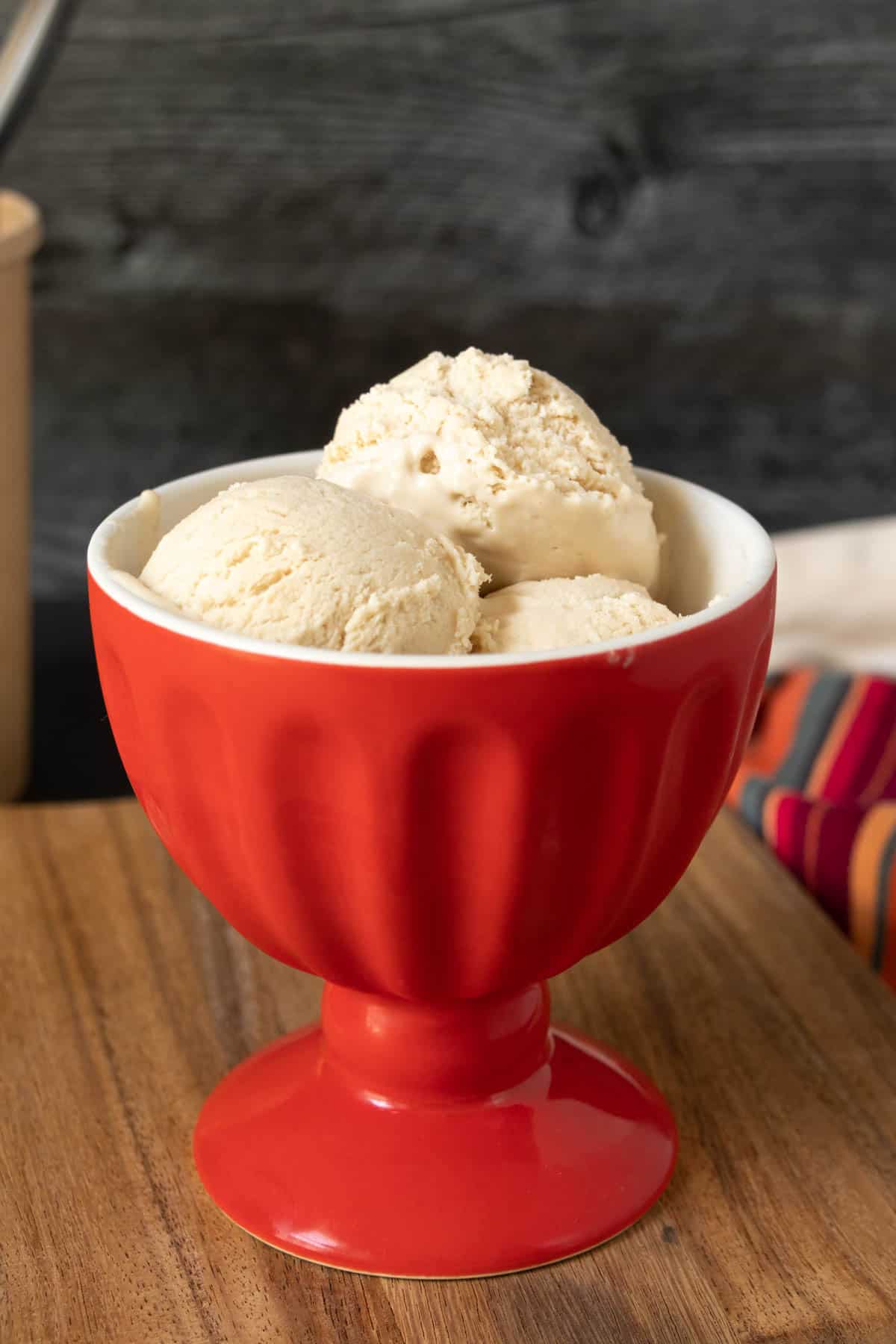 Red bowl of no-churn ice cream with a black wooden background.