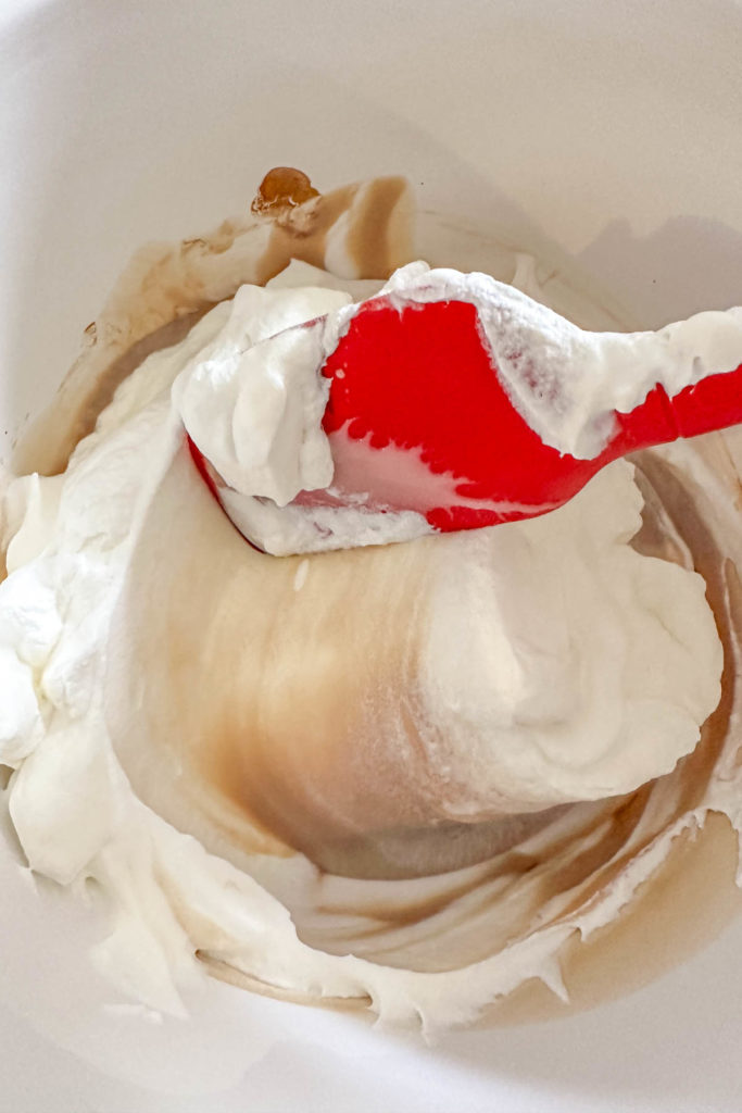 Folding whipped cream into sweetened condensed milk.