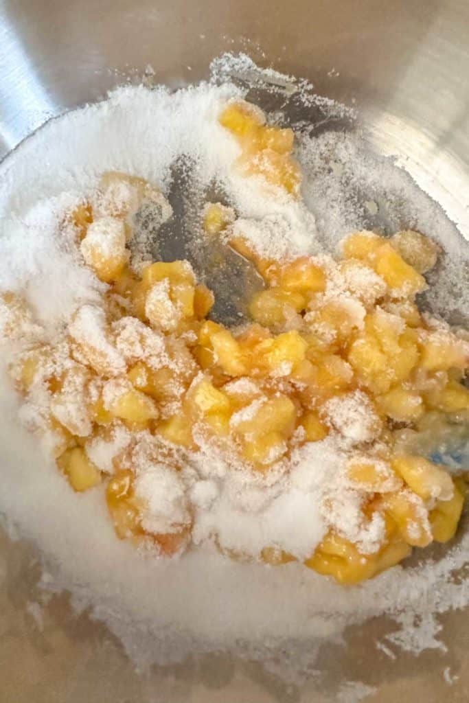 Mixing peaches and sugar in a saucepan.