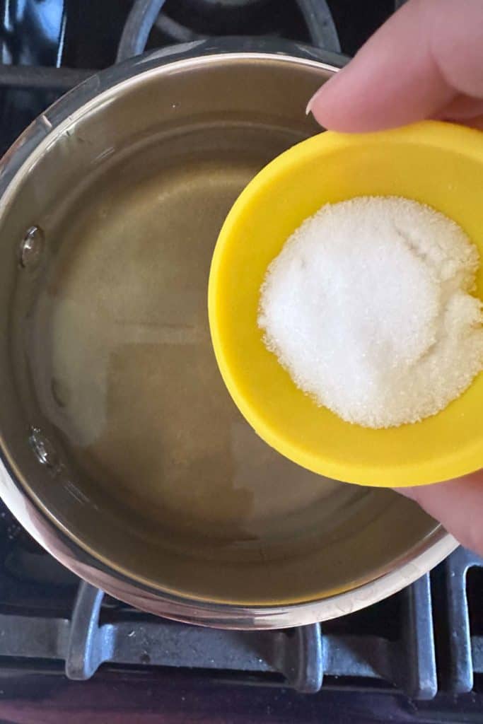 Adding salt to brine to make pickles.