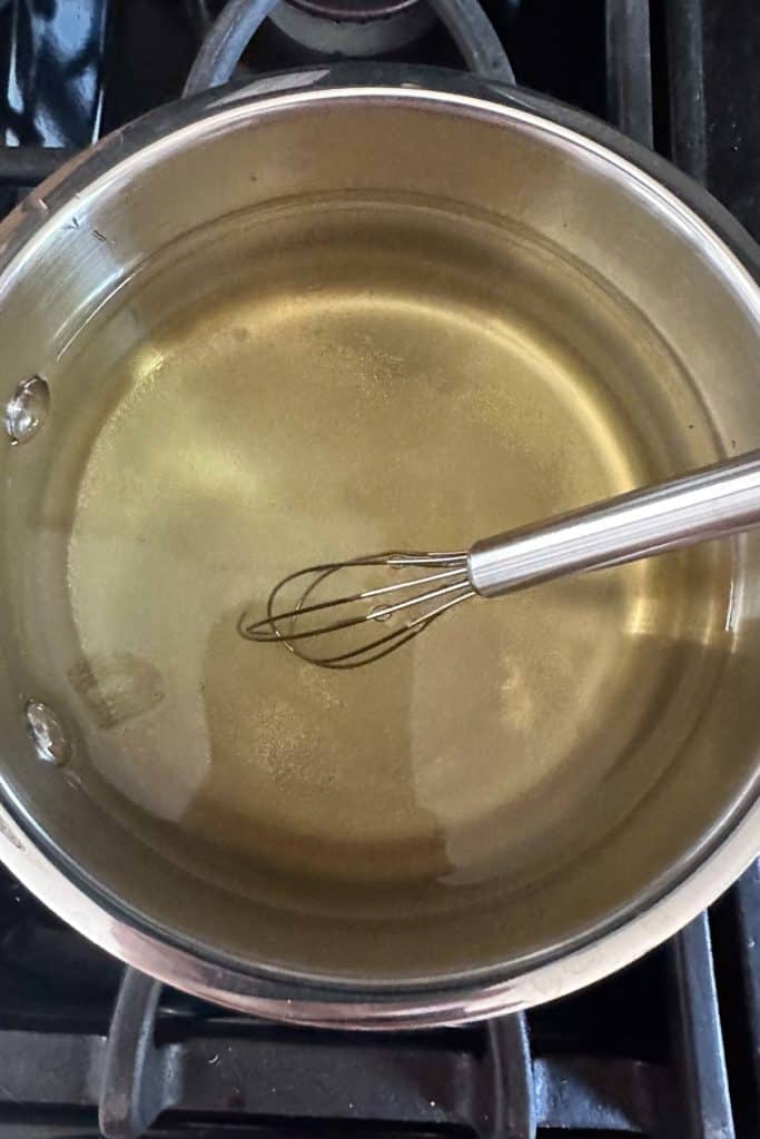 Pot of pickling brine being whisked to dissolve sugar and salt.