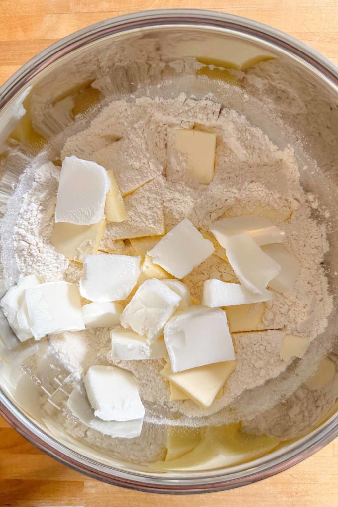Pieces of butter and shortening being added to flour for pie dough.