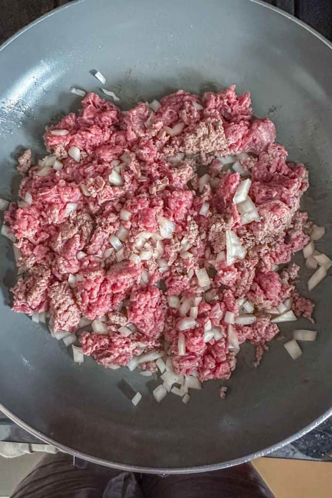 Onion and ground bison being sauteed in a pan.
