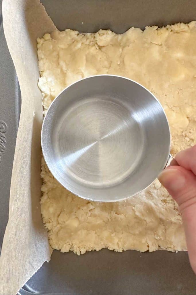 Pressing pie bar crust in the pan.