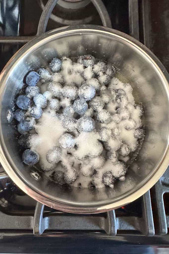 Saucepan with blueberries and sugar.