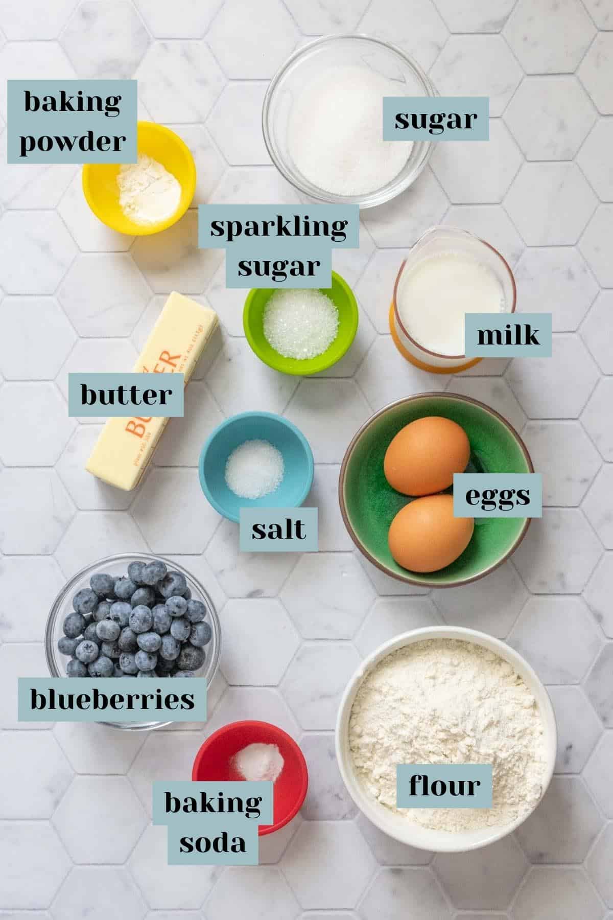 Ingredients for blueberry scones on a tile surface with labels.