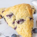 Close up of blueberry scone with blueberries next to it.